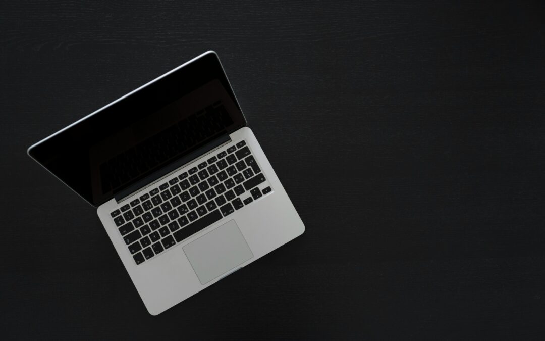 A silver laptop open on a black background