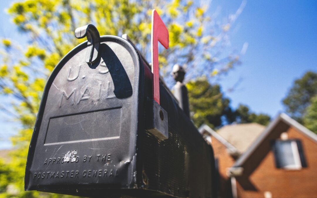 A photo of a black mailbox with its red flag raised.